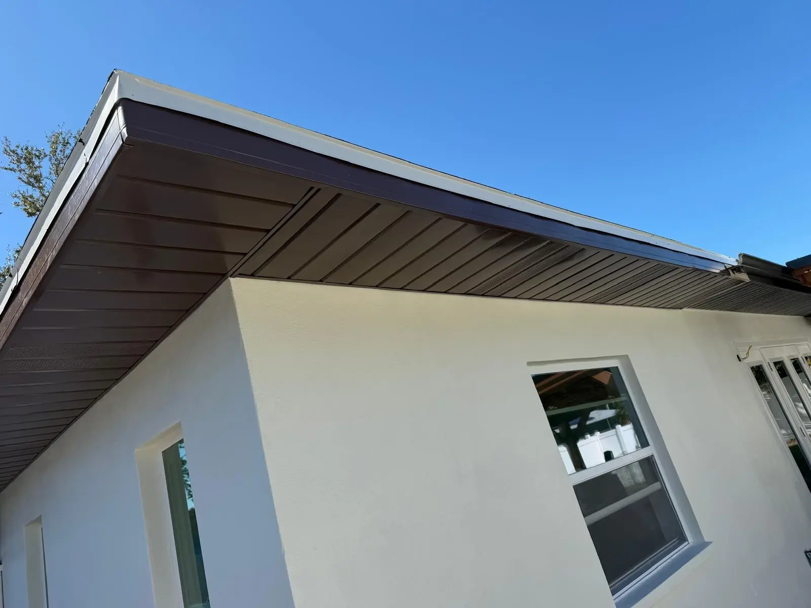 Smooth white stucco exterior with new windows beneath a dark soffit.